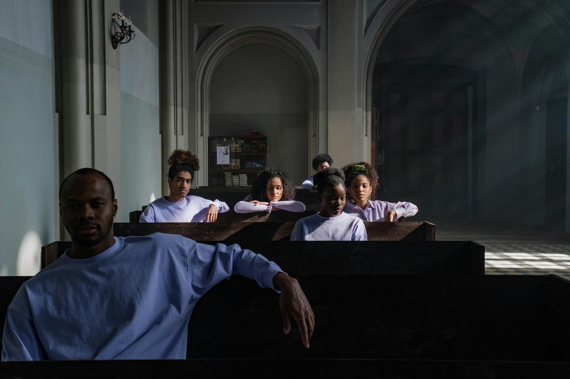 Ludzie zamyśleni w ławkach kościoła w świetle wpadającym przez okna