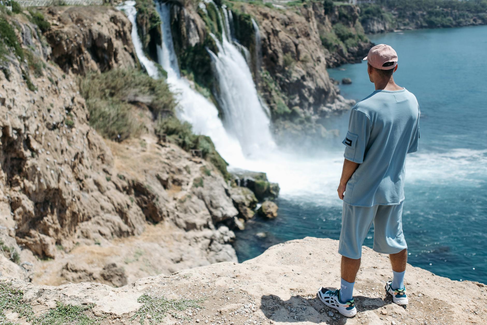 Mężczyzna w casualowym stroju patrzy z klifu na wodospad w Turcji