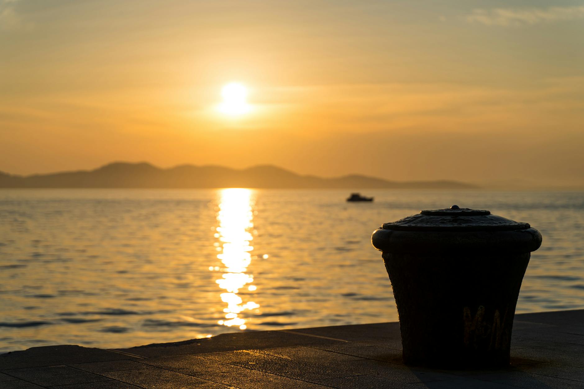 Zachód słońca nad Adriatykiem z polerem cumowniczym w porcie Zadaru