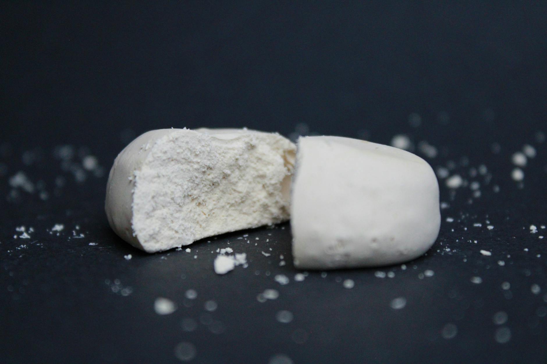 Zbliżenie na kruchy polvoron przełamany na pół na czarnym tle