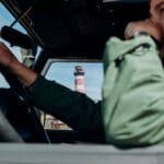 Szlakiem latarni morskich: pomysł na road trip wzdłuż wybrzeża Kobieta prowadzi auto, a za oknem widać latarnię morską